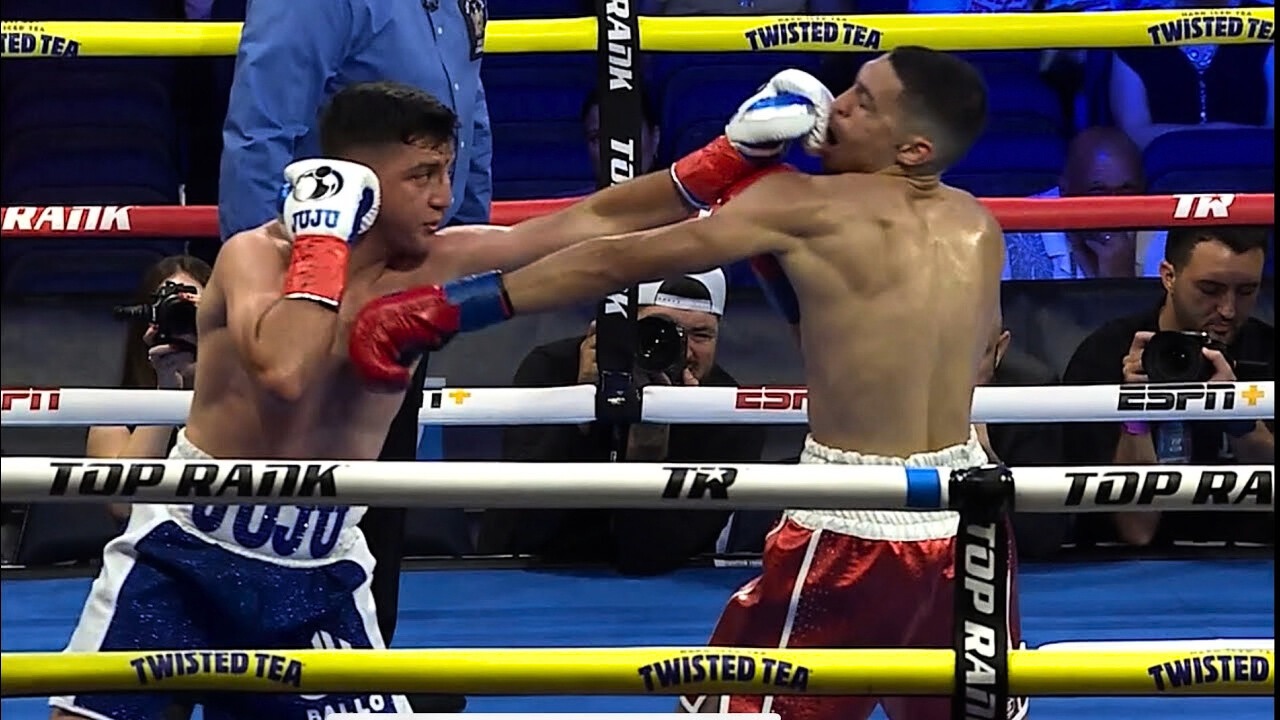 Julius Ballo landing a punch in the ring in the red JUJU trunks