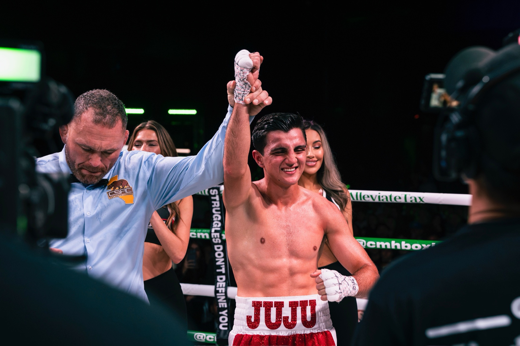 Julius Ballo with his hand raised after a win, in the red JUJU trunks